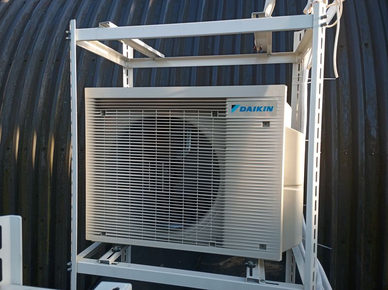 Daikin išorinis blokas metaliniame rėme prie gofruotos sienos